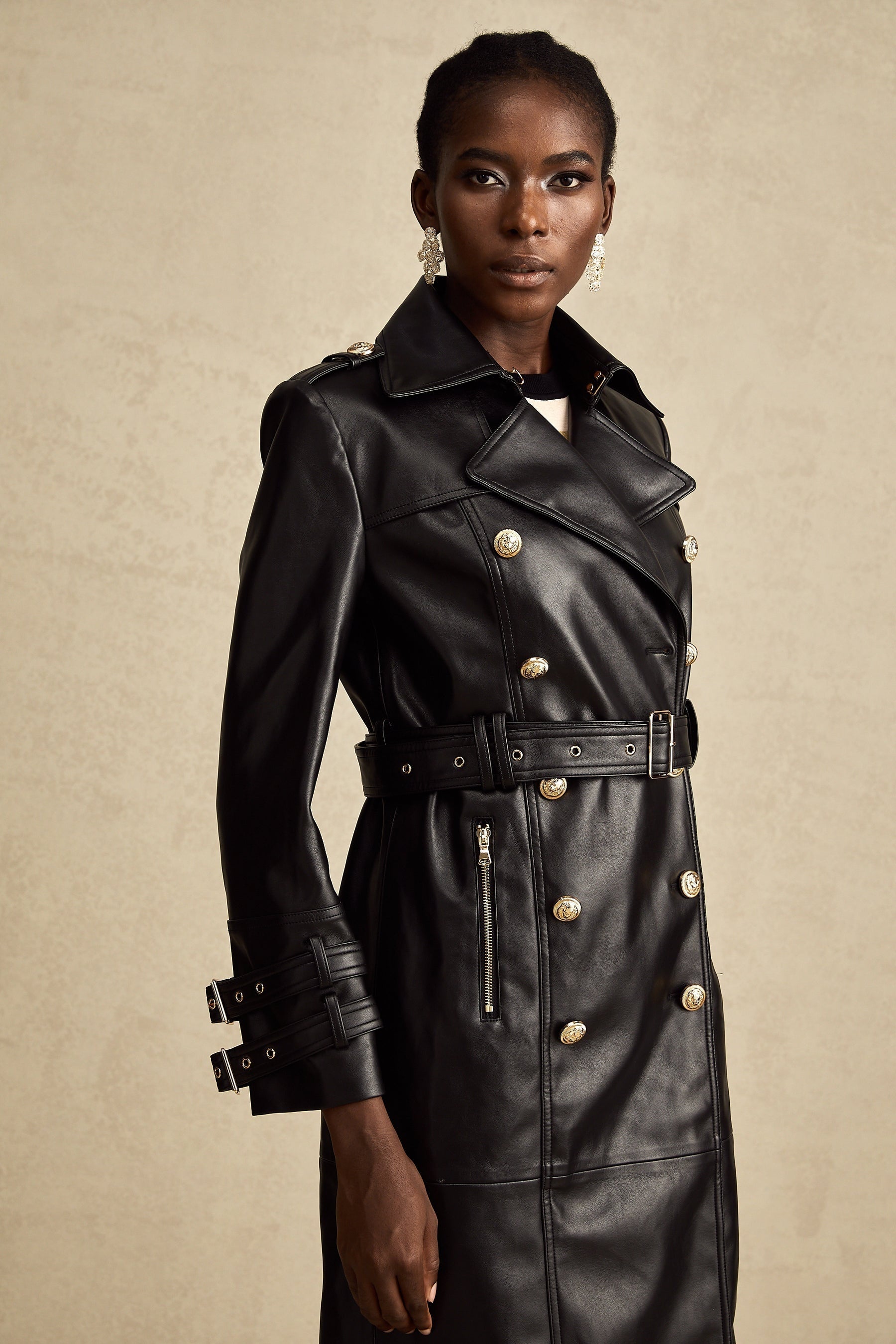 black doublebreasted leather coat with a belt cinched at the waist