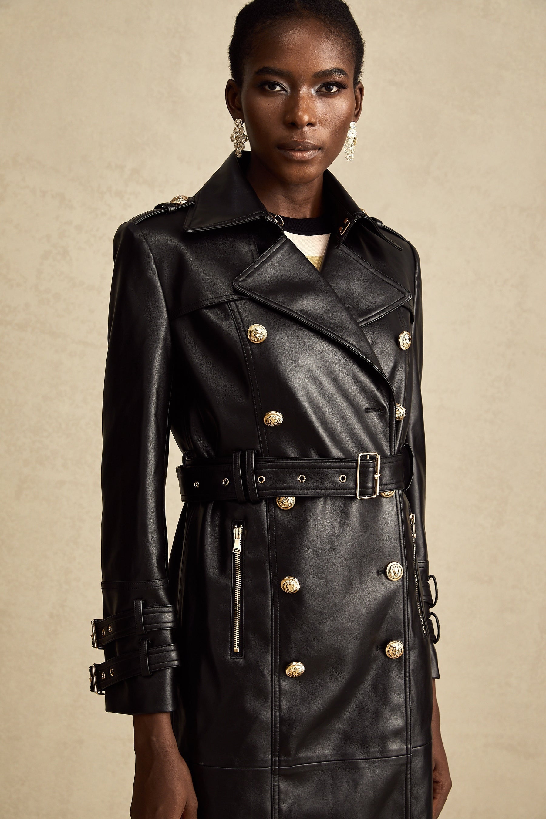 black doublebreasted leather coat with a belt cinched at the waist