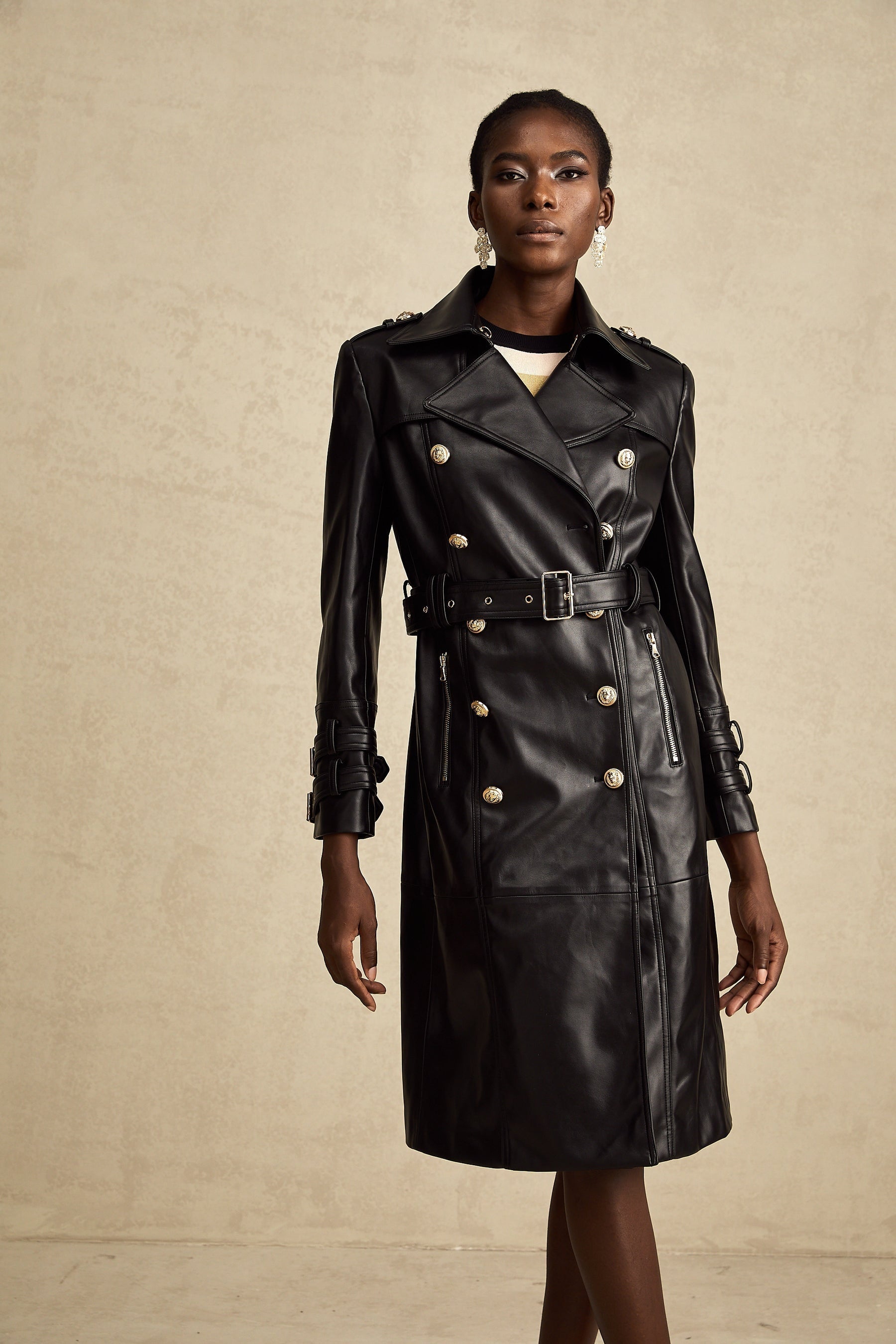 black doublebreasted leather coat with a belt cinched at the waist