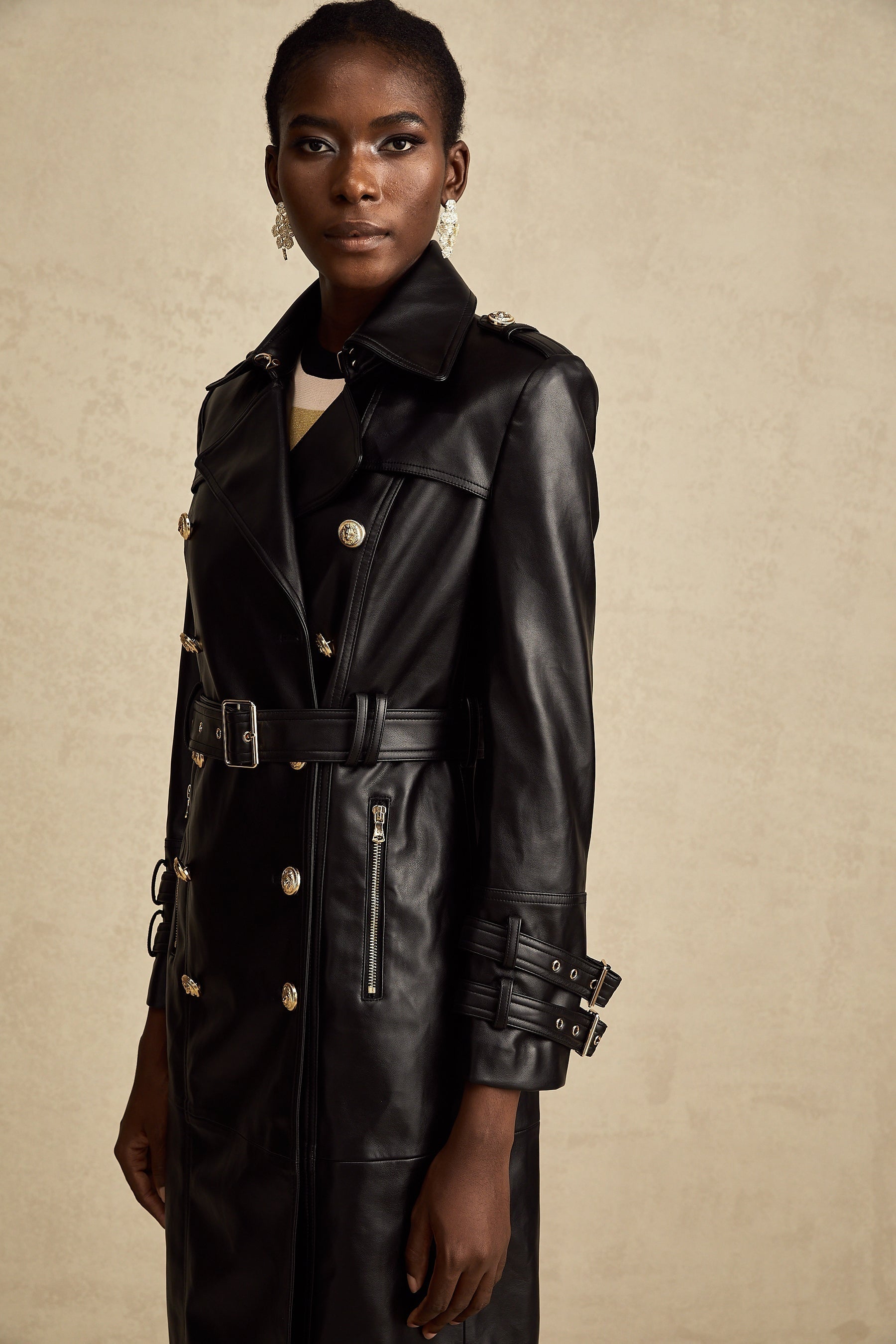 black doublebreasted leather coat with a belt cinched at the waist