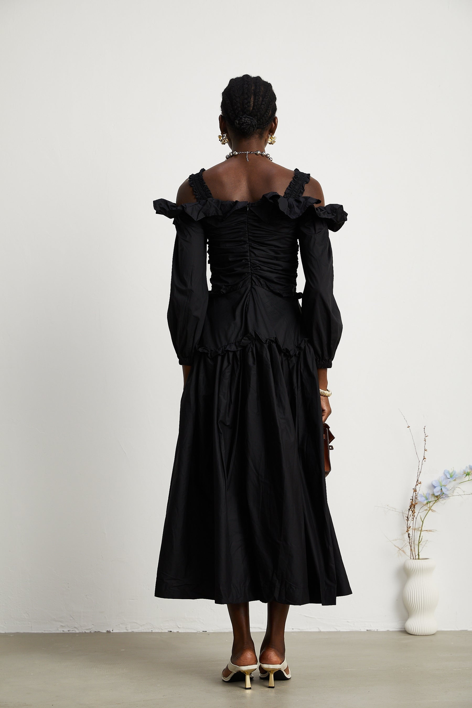 A black pleated midi dress with ruffled details and a flowy silhouette