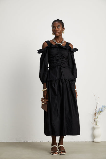 A black pleated midi dress with ruffled details and a flowy silhouette