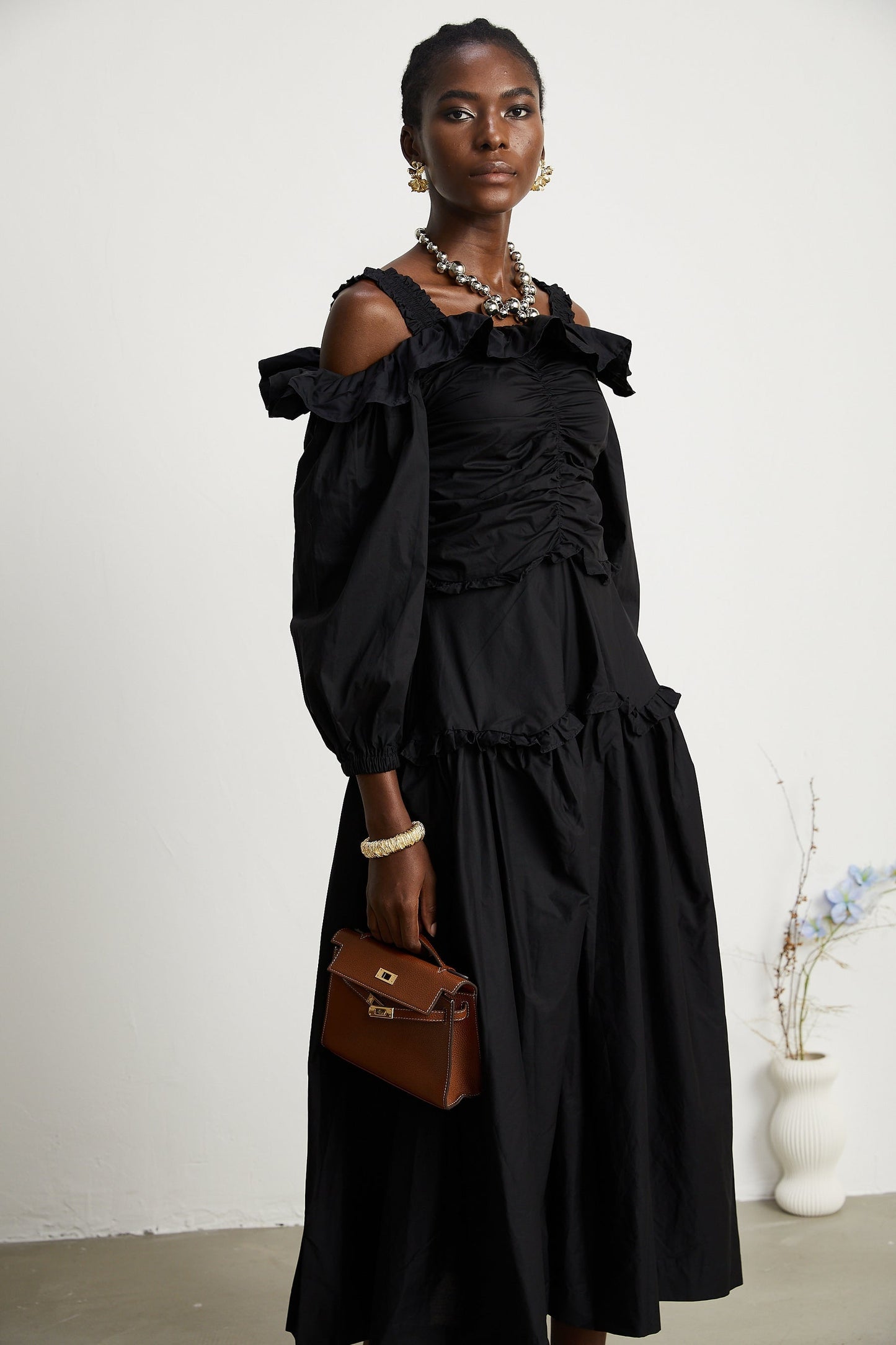 A black pleated midi dress with ruffled details and a flowy silhouette