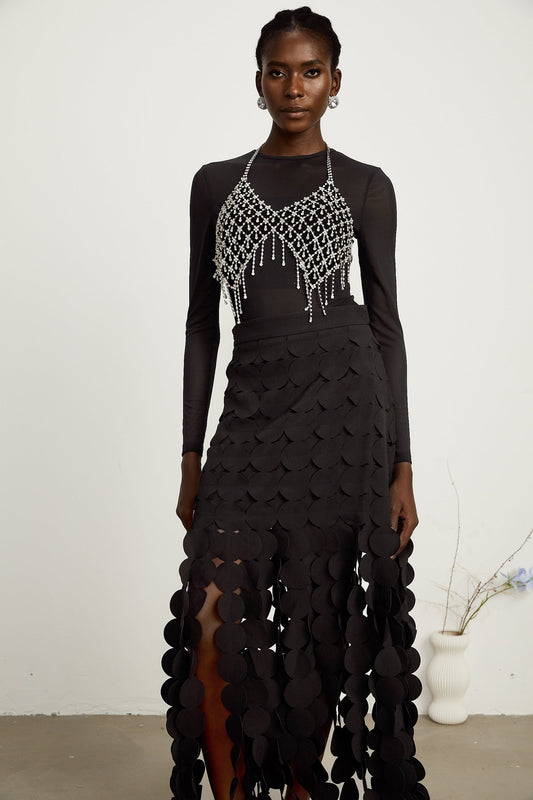 A black midi skirt with a disc design pattern and fringed hem worn