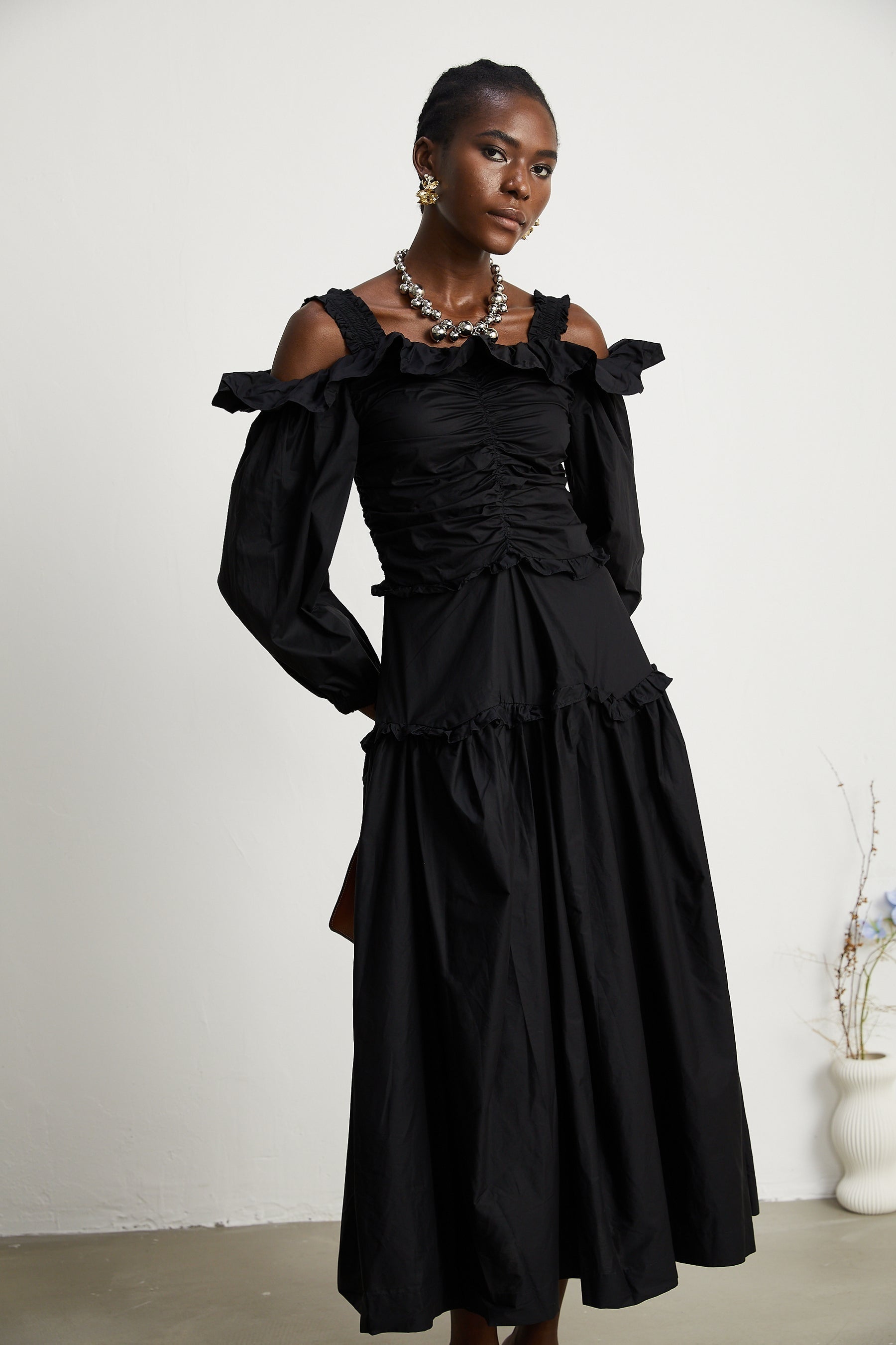 A black pleated midi dress with ruffled details and a flowy silhouette