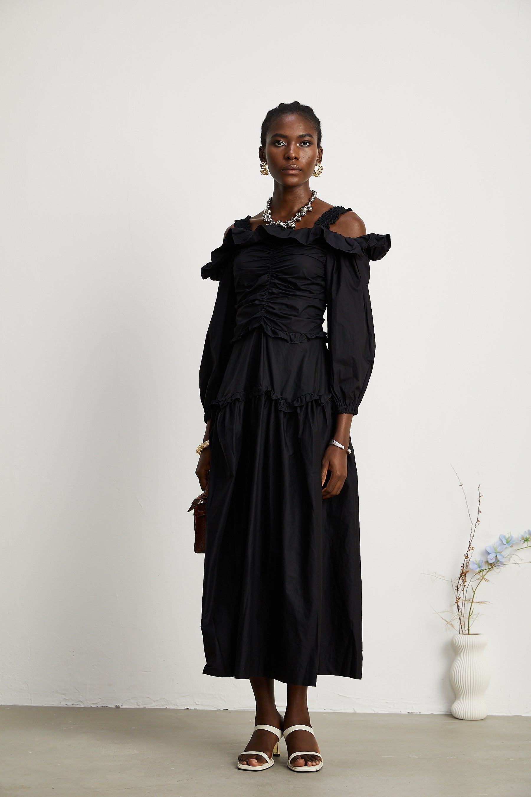 A black pleated midi dress with ruffled details and a flowy silhouette