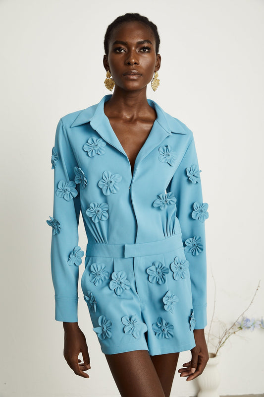 A blue bodysuit with floral applique details