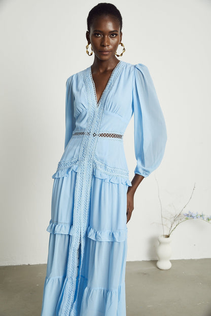 A blue maxi dress with cutout details and ruffled accents featuring a long flowy silhouette