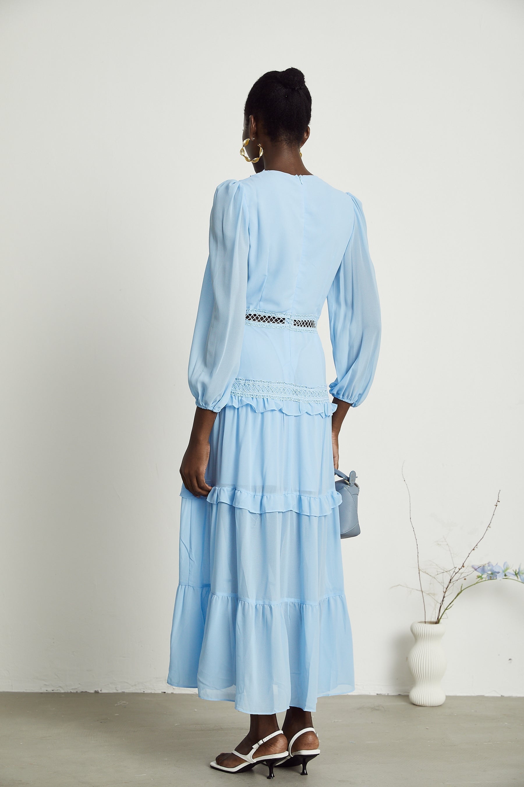 A blue maxi dress with ruffles and cutout details featuring a long flowing skirt and feminine silhouette