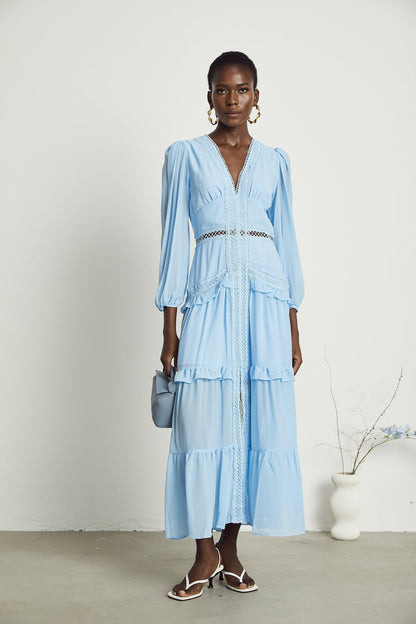 A blue maxi dress with ruffles and cutout details featuring a long flowing skirt and feminine silhouette