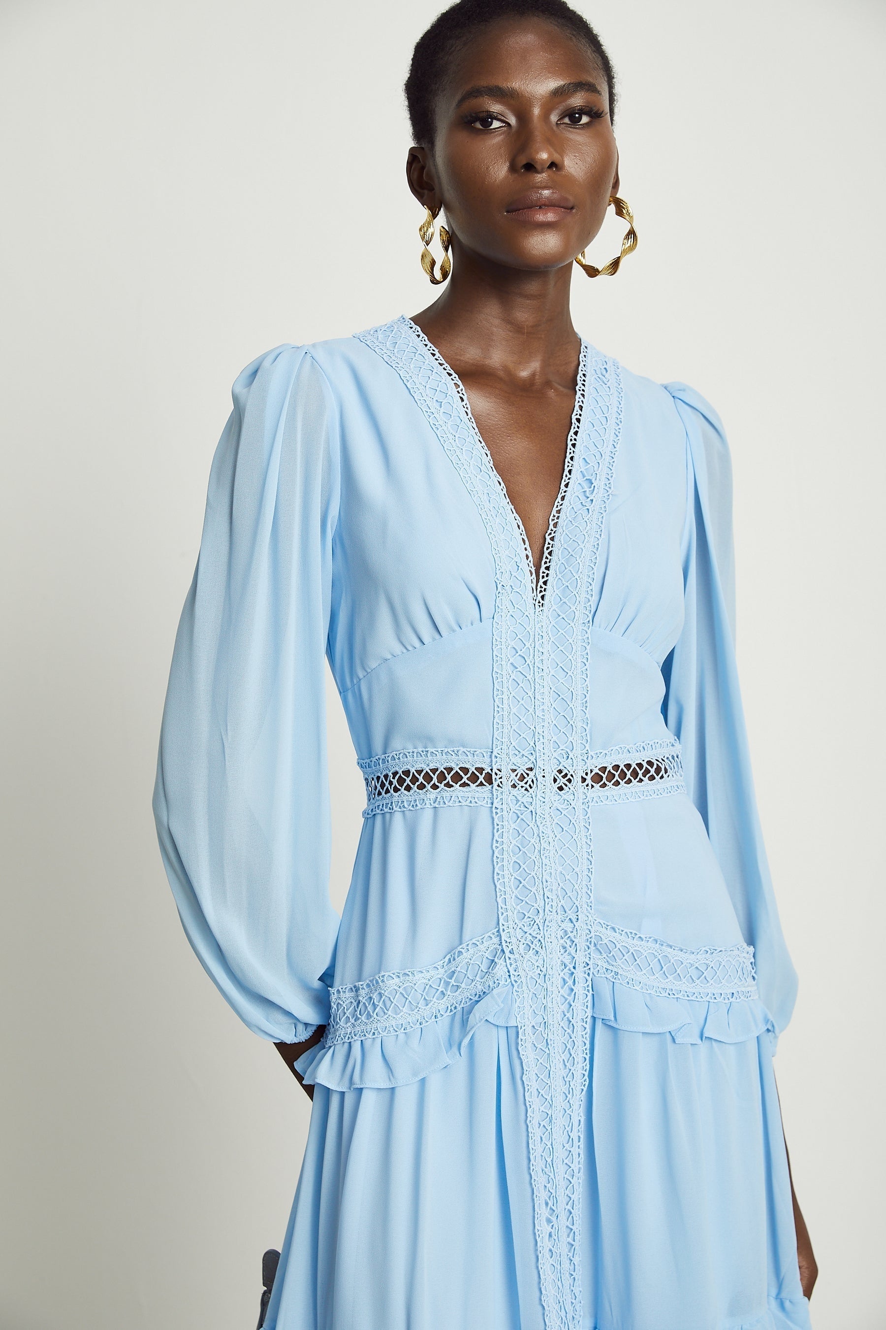 A blue maxi dress with ruffles and cutout details featuring a long flowing skirt and sleeveless design