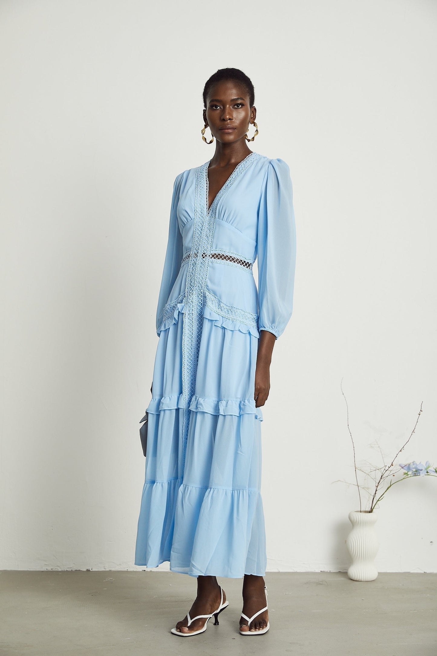 A blue maxi dress with ruffles and cutout details featuring a long flowing skirt and feminine silhouette