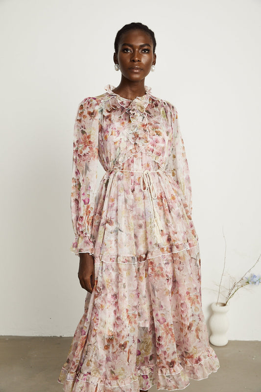 A long pink maxi dress with a floral print pattern and frilled details