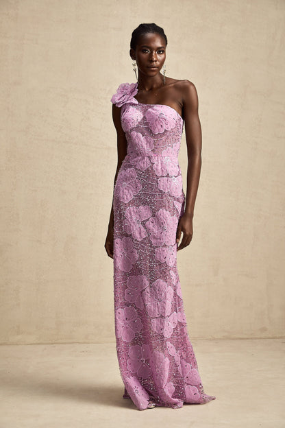 A long purple maxi dress with floral applique details adorning the fabric