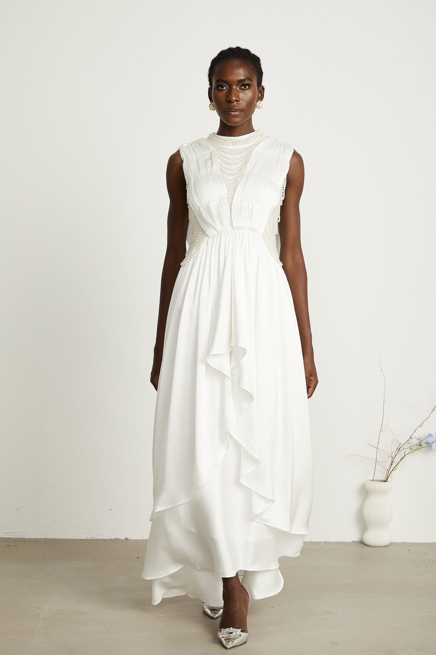 A long white pleated maxi dress with faux pearl embellishments