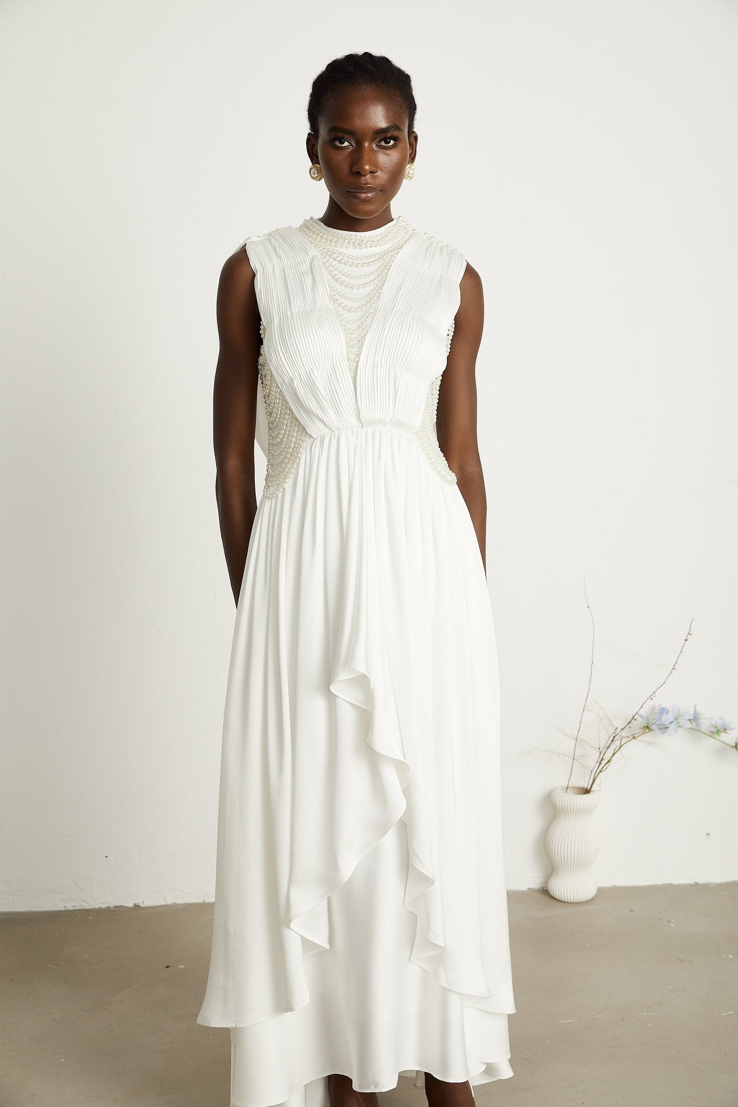 A long white pleated maxi dress with faux pearl embellishments