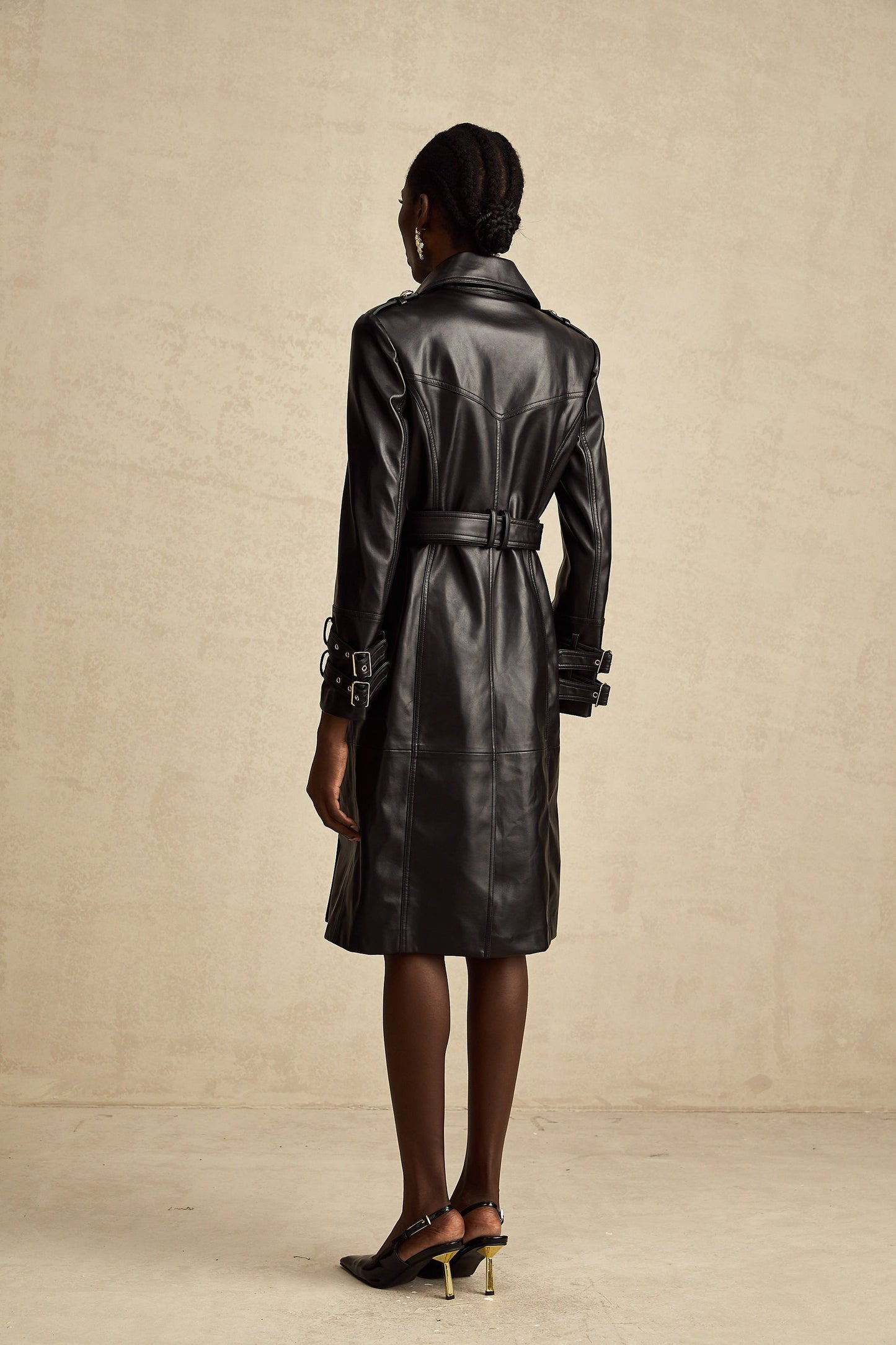 black doublebreasted leather coat with a belt cinched at the waist