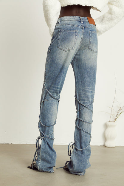 A pair of blue denim jeans with distinctive strap details visible on the waistband or pockets named Geraldine