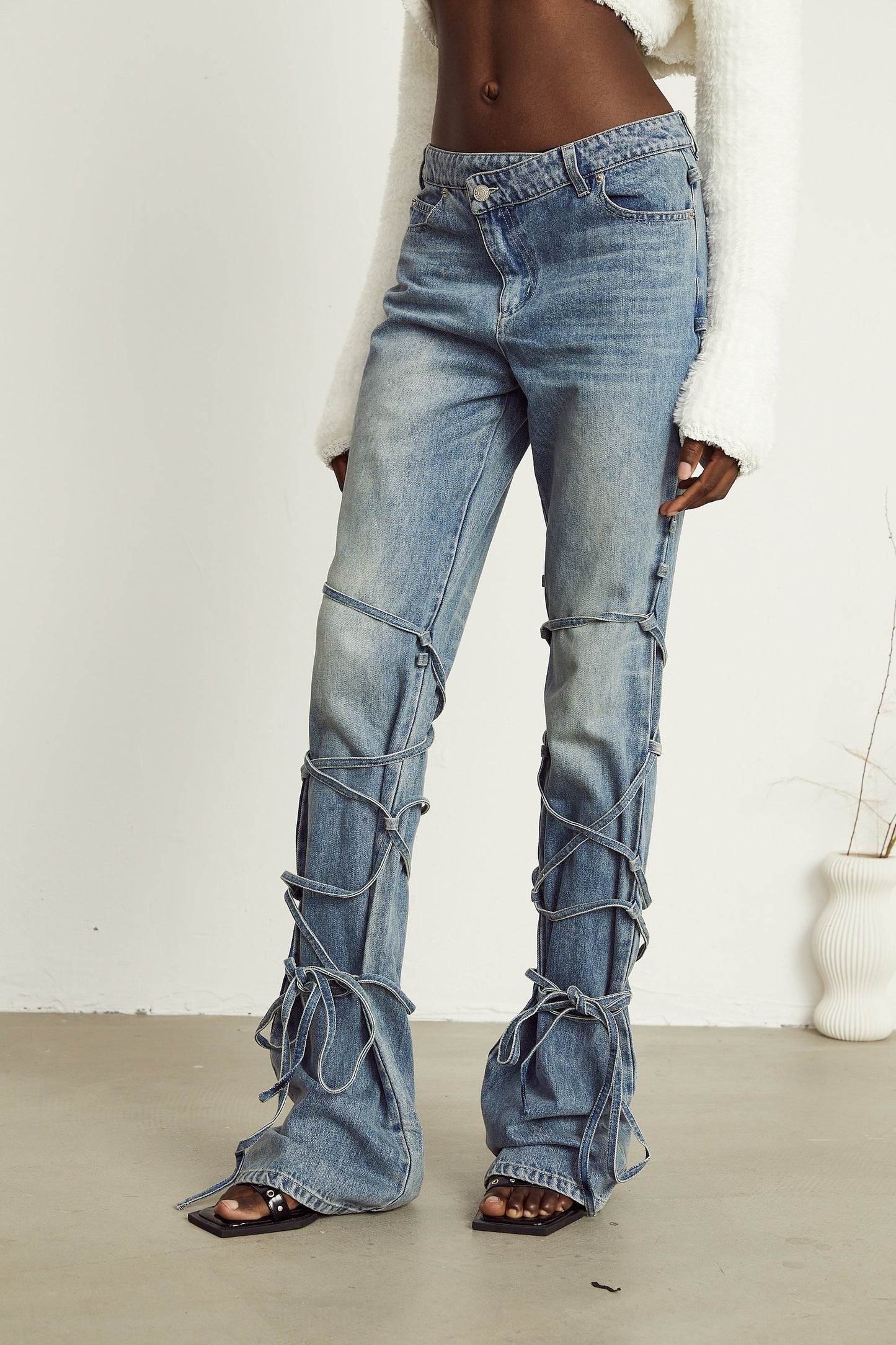 A pair of blue jeans with distinctive strap details featuring the name Geraldine