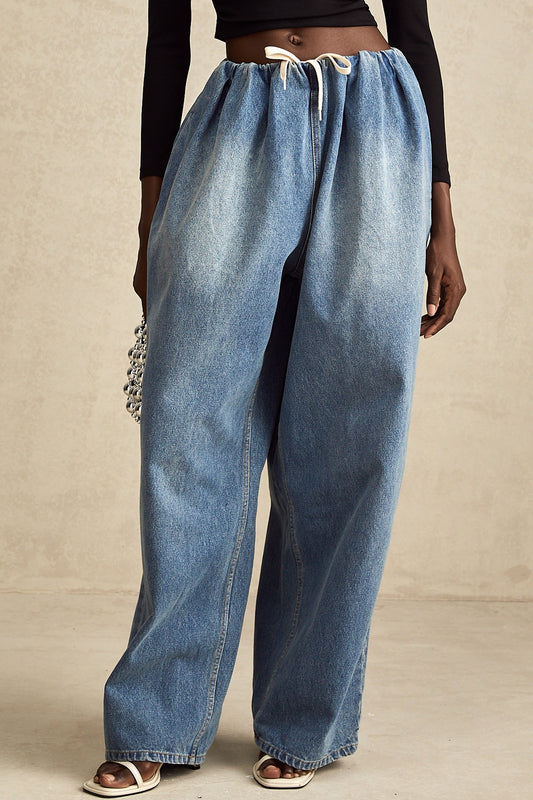 A pair of light blue denim trousers with pleated detailing and a low rise waist