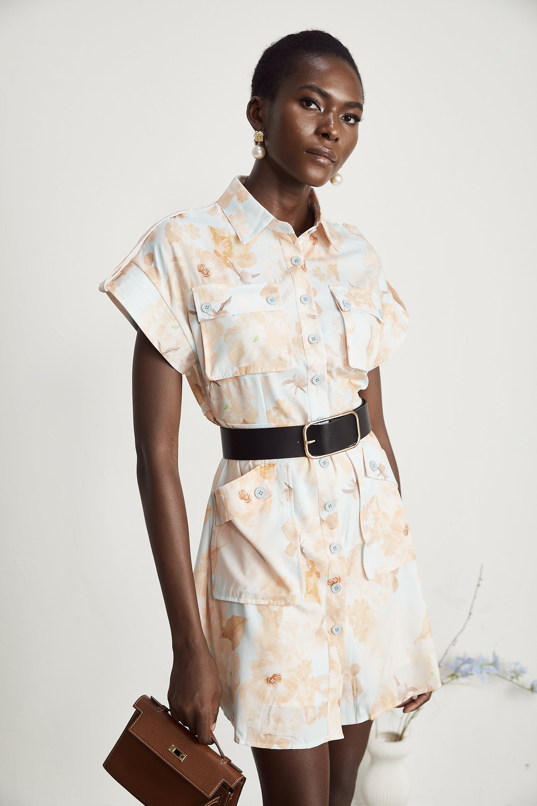 A short black mini dress with a collared shirt style top and a fabric belt tied at the waist