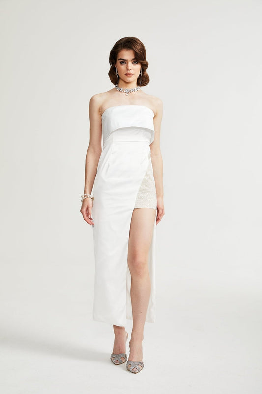 A white off the shoulder dress on a mannequin or model showing the flowy feminine design of the Zafiritha dress