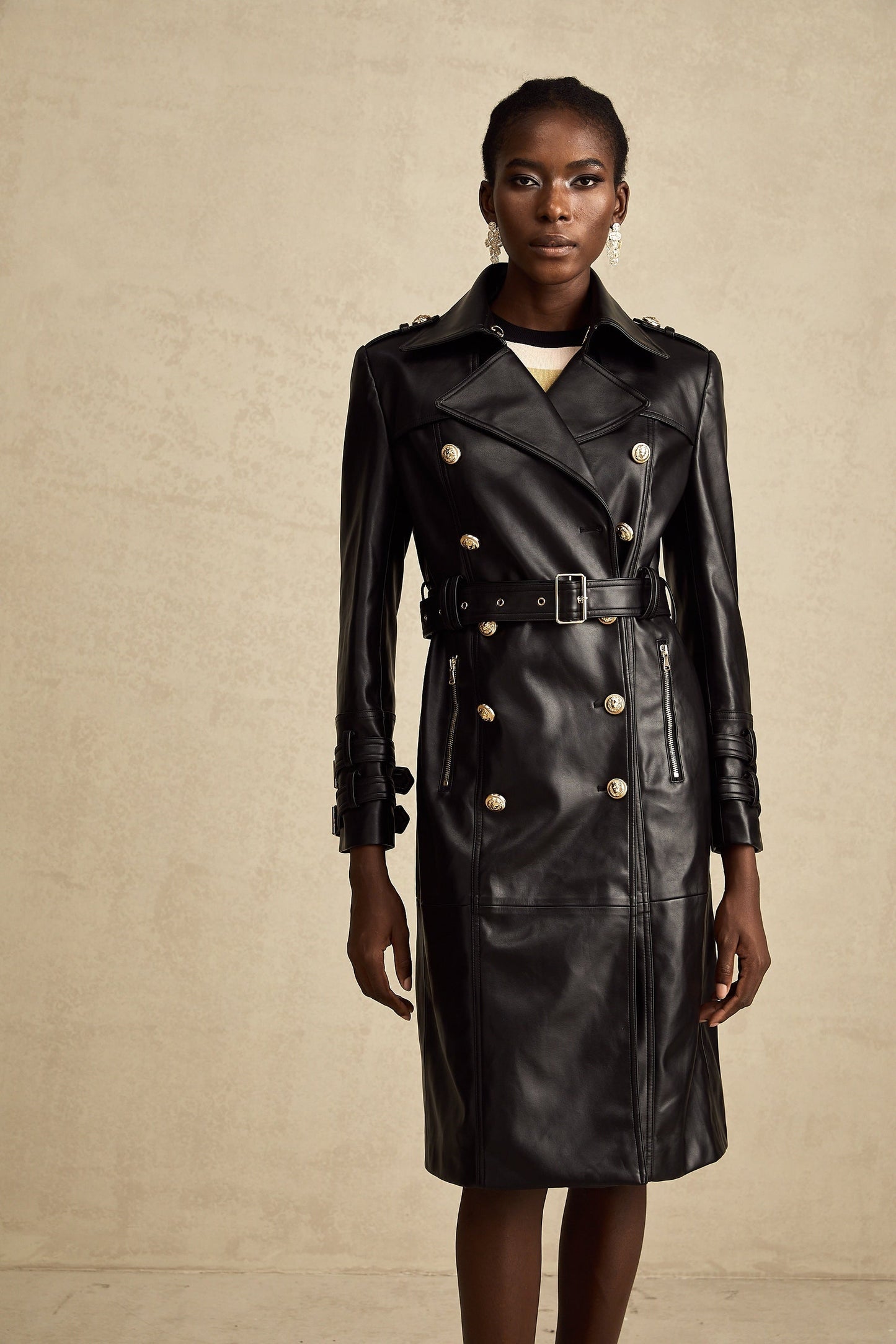 black doublebreasted leather coat with a belt cinched at the waist