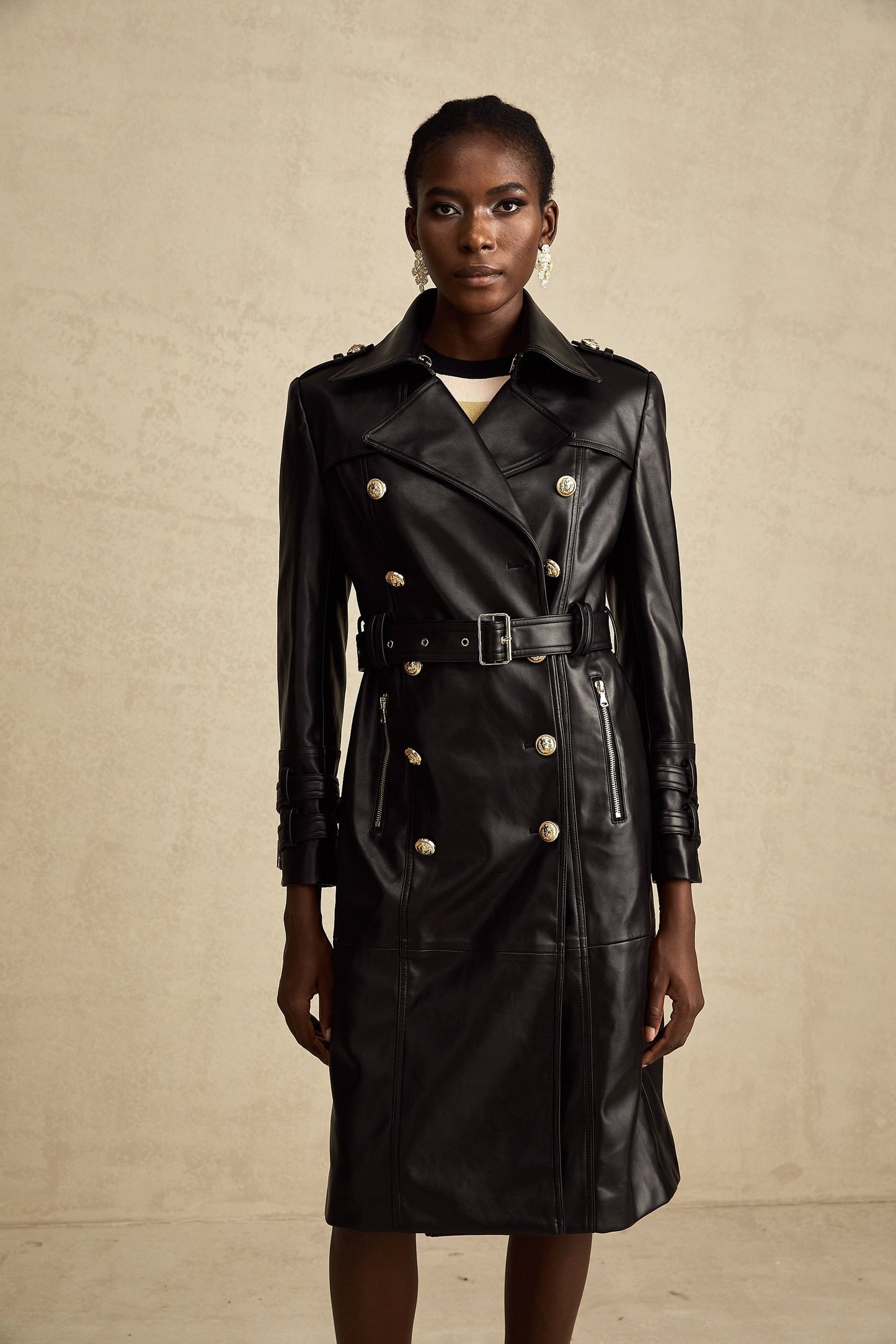 black doublebreasted leather coat with a belt cinched at the waist