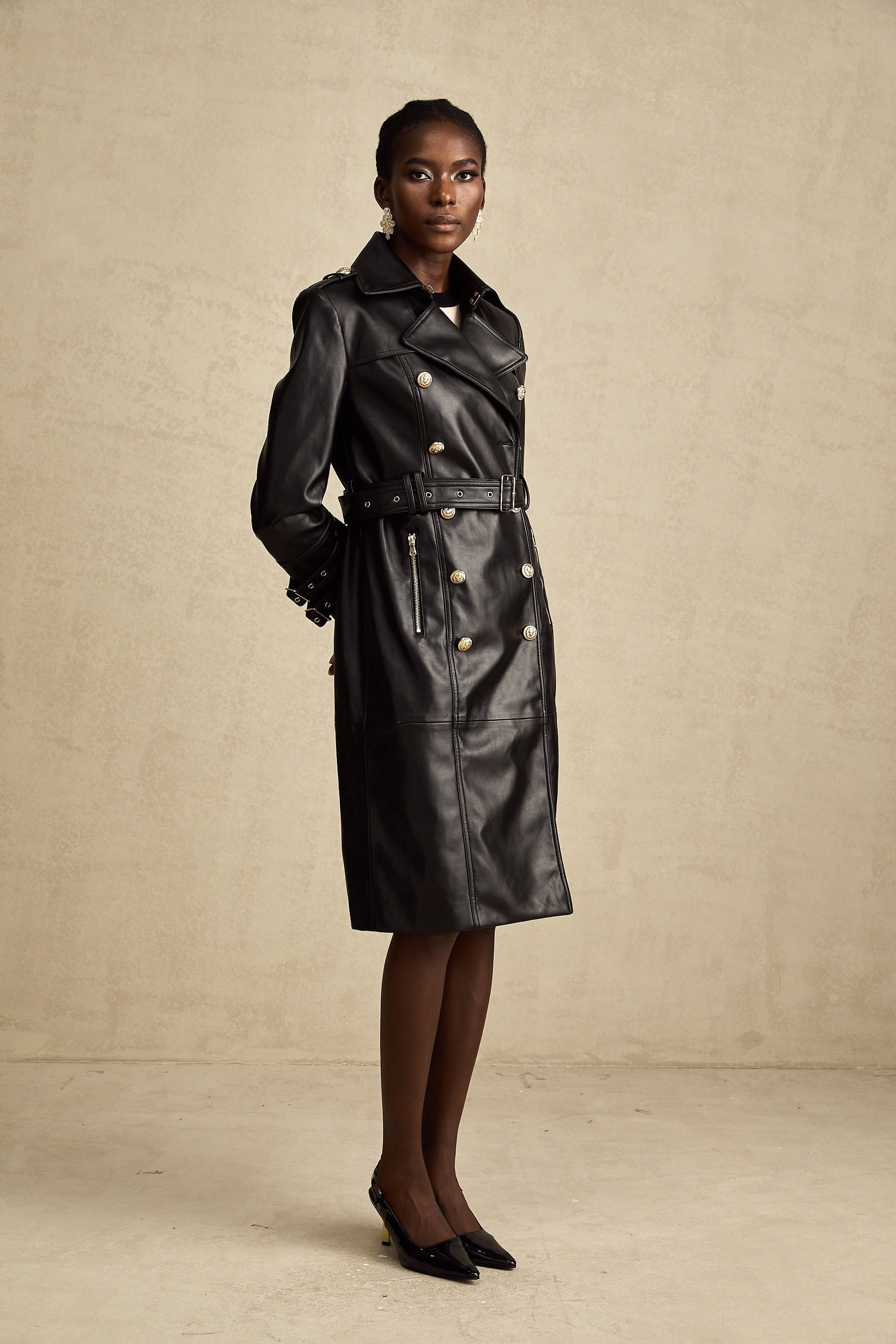 black doublebreasted leather coat with a belt cinched at the waist