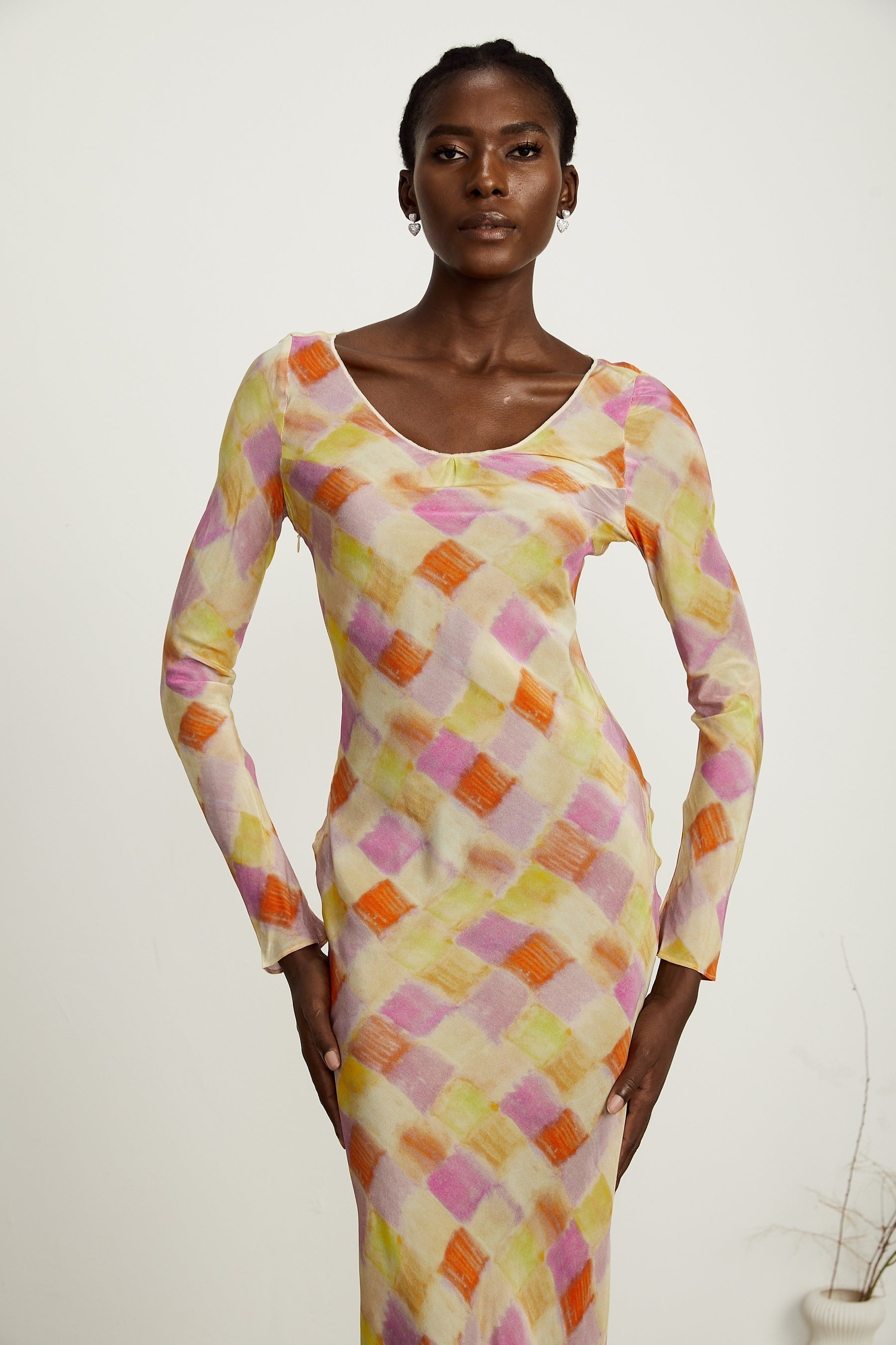 A woman wearing a flared midi dress with a color block design featuring a check pattern The dress has a fitted bodice and flares out at the waist in a graceful silhouette