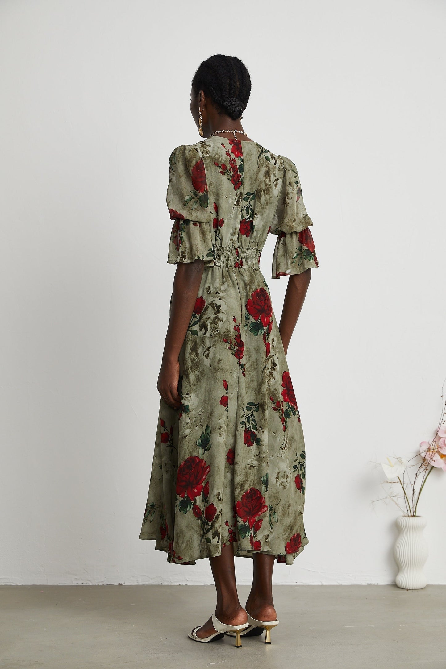 A woman wearing a floral print midi dress with a V neck pattern and flowing silhouette