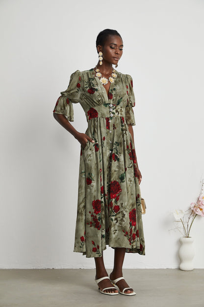 A woman wearing a floral print midi dress with a V neckline standing in a casual pose against a plain background