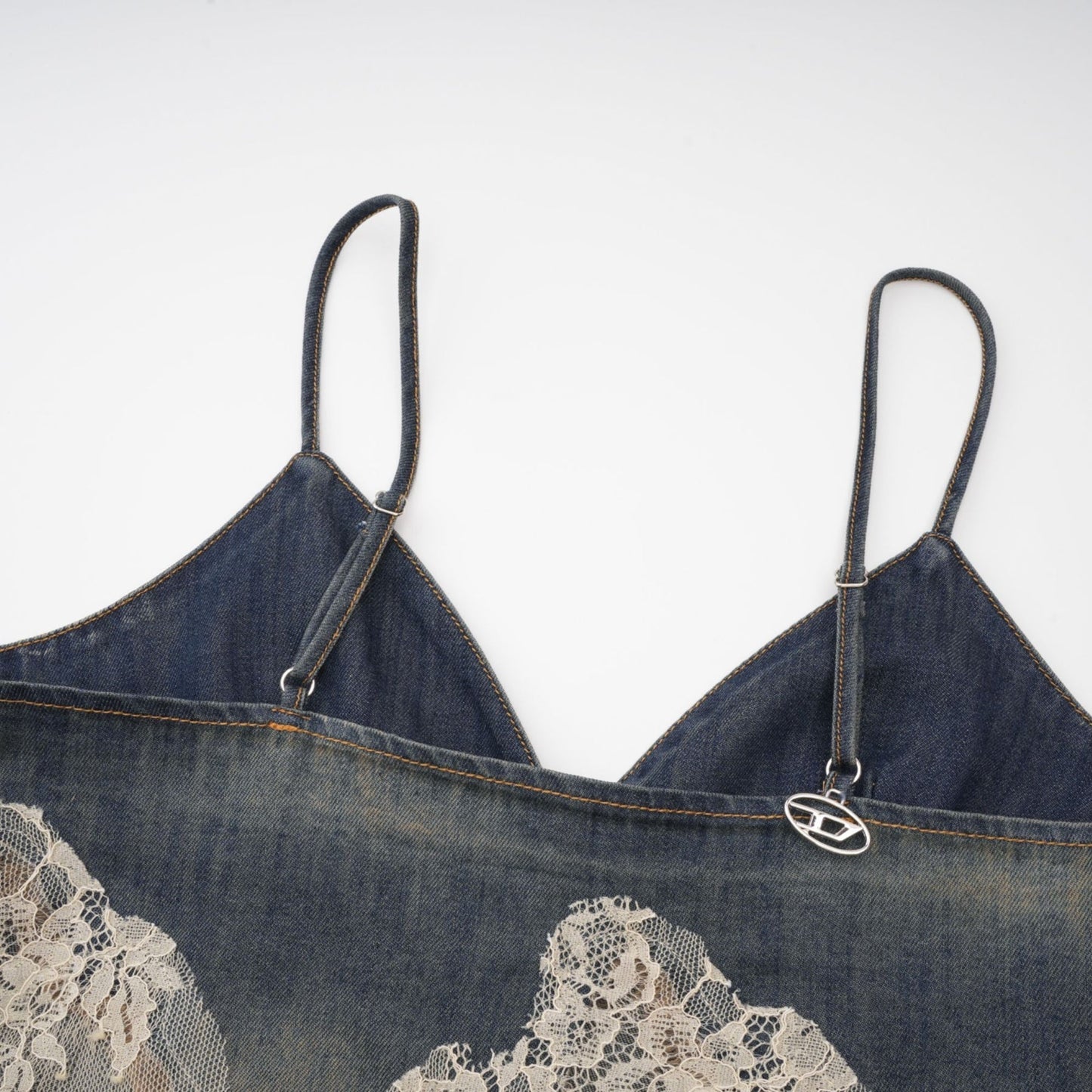 A woman wearing a matching denim outfit consisting of a lace detailed top and shorts standing against a plain background