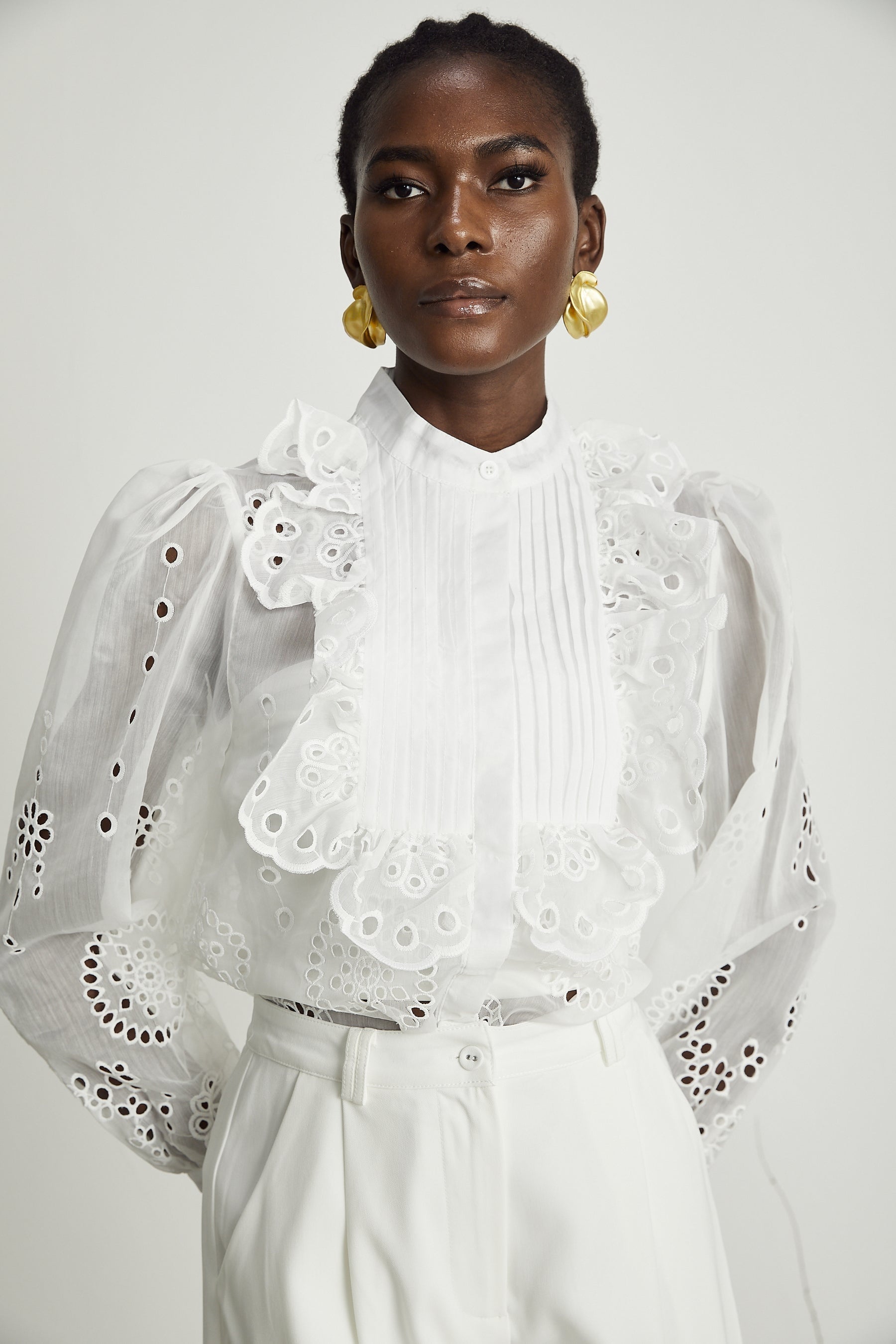 A woman wearing a matching set consisting of a white ruffled shirt with cutout details and coordinating shorts