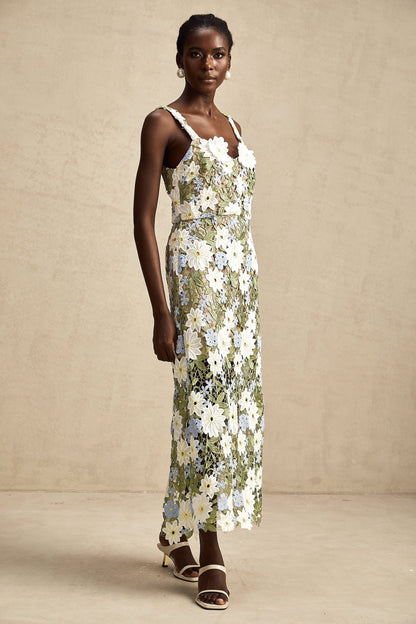 A woman wearing a midi length dress with floral embroidery and hollow carved details throughout the fabric