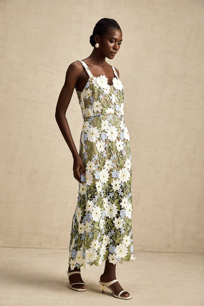 A woman wearing a white midi dress with floral embroidery and hollow carved details