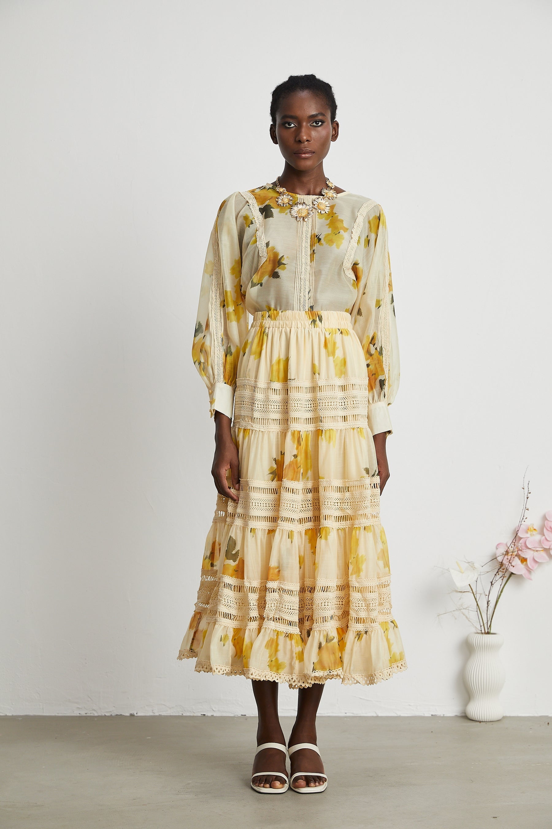 Young woman wearing yellow floral print lace dress standing indoors