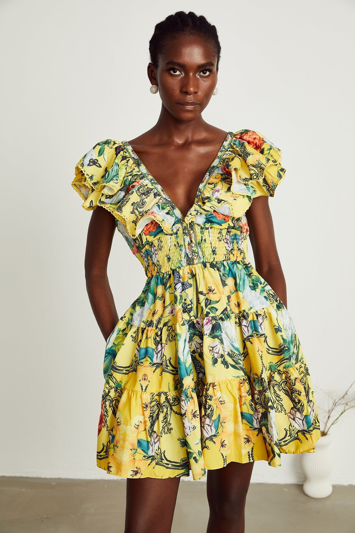 A yellow mini dress with a floral print pattern and ruffled details