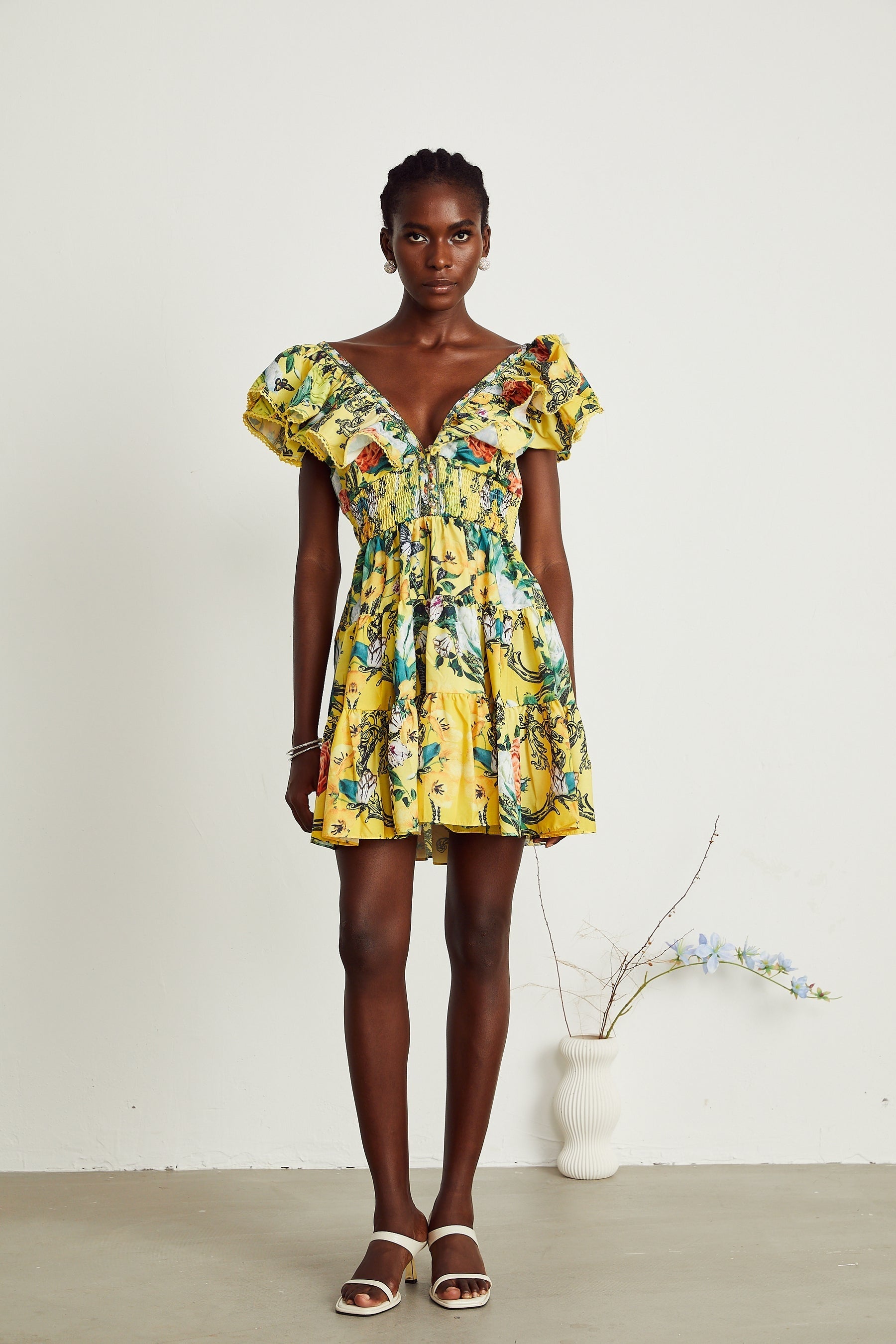 A yellow mini dress with ruffled details and a floral print pattern