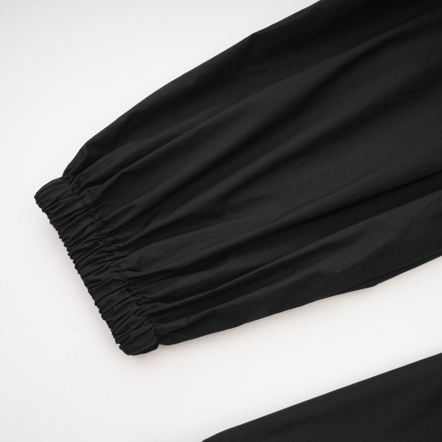 A black pleated midi dress with ruffled details and a flowy silhouette