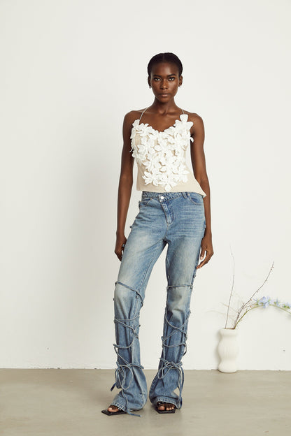 Blue denim jeans with decorative strap details on the waist and legs