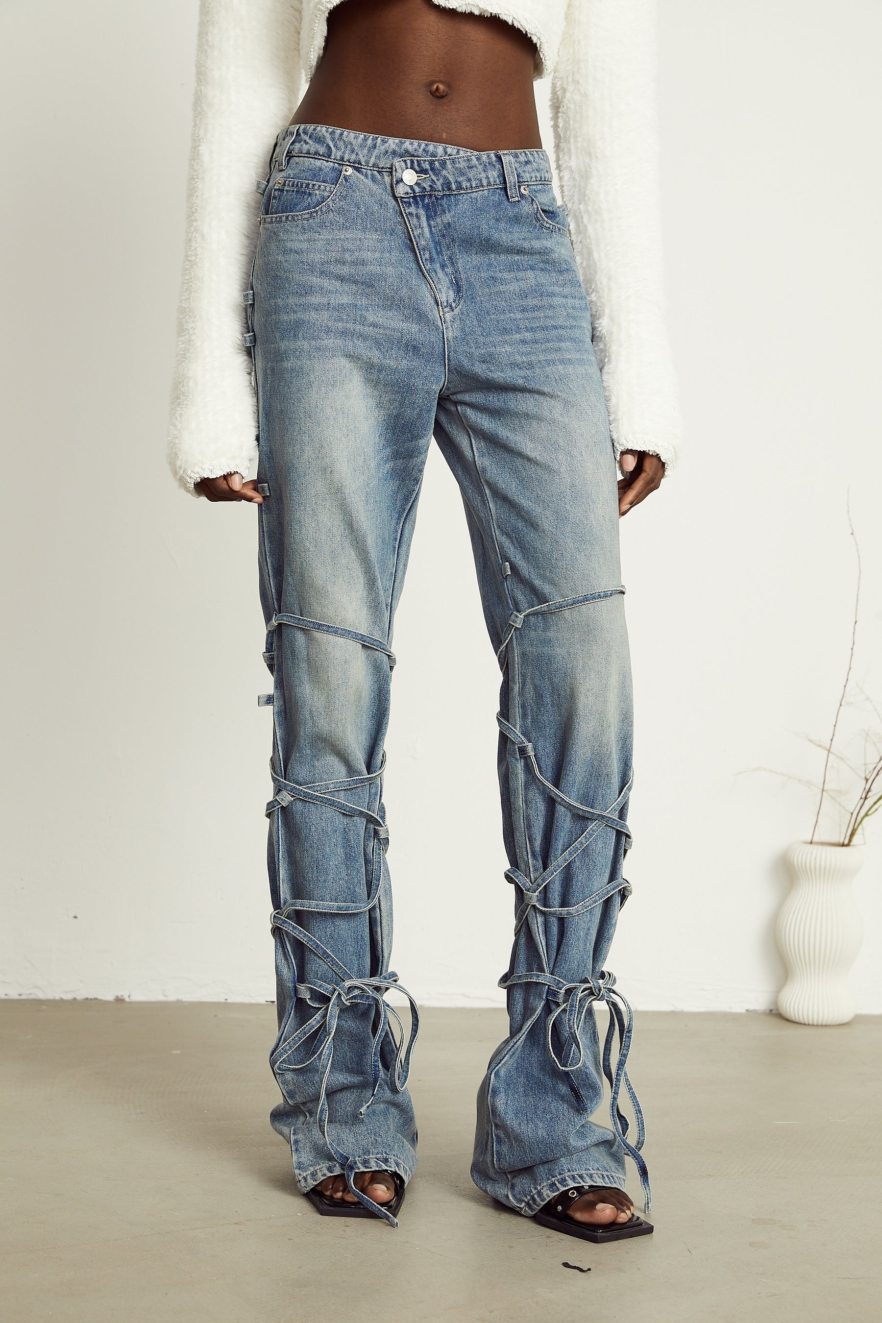 Blue denim jeans with decorative straps on the waist and legs