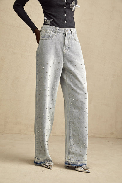 Blue denim jeans with wide legs and high waist adorned with small rhinestones scattered across the fabric