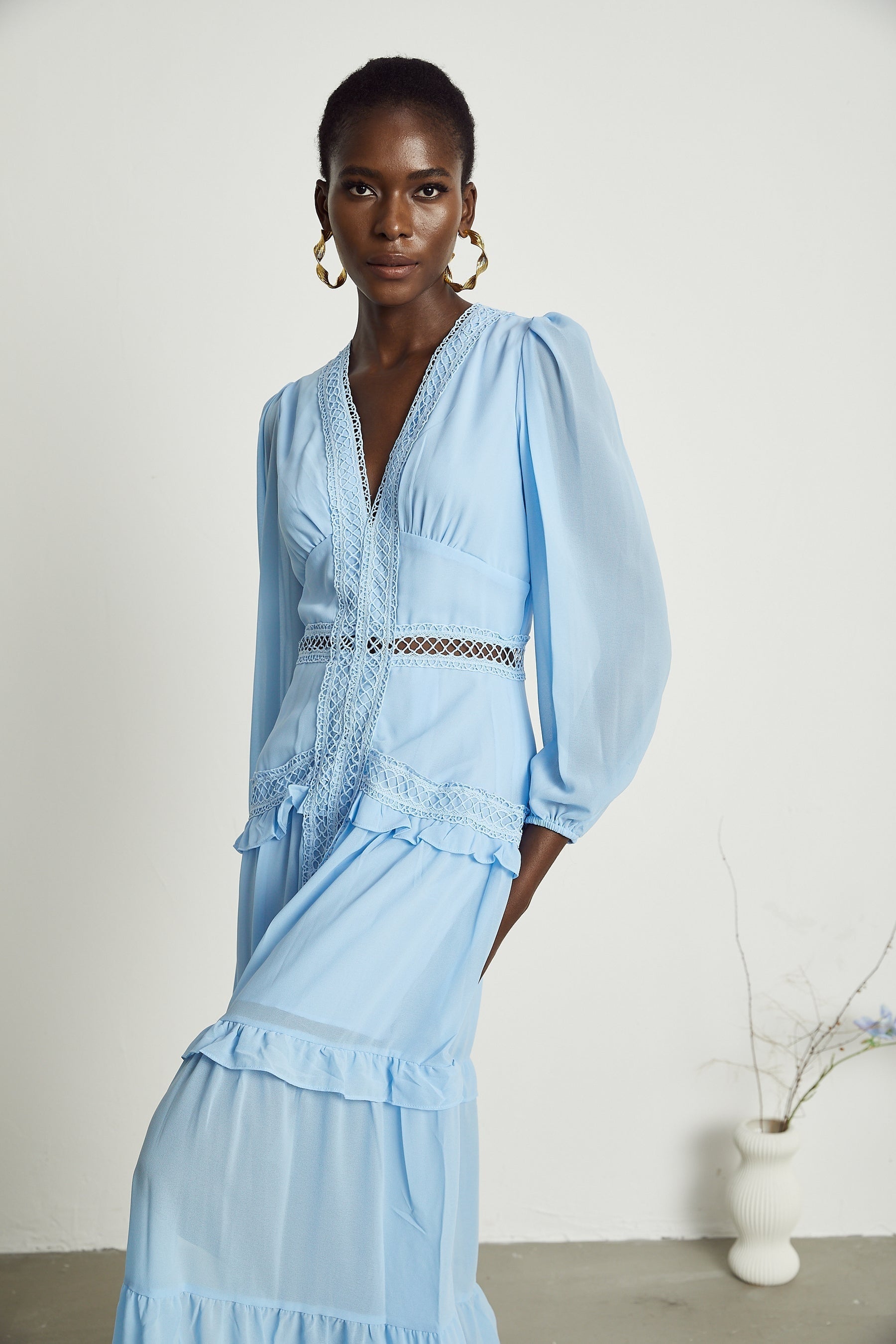 A blue maxi dress with ruffles and cutout details featuring a long flowing skirt and feminine silhouette