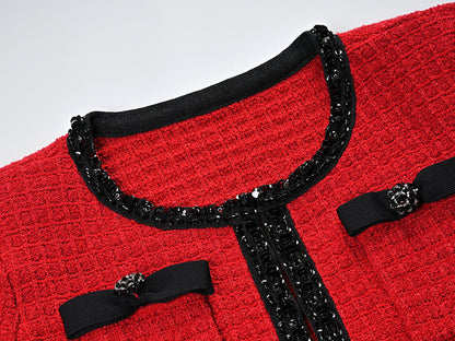 Striking red knitted wool jacket with black trim and decorative bows paired with a matching skirt featuring a flared hem