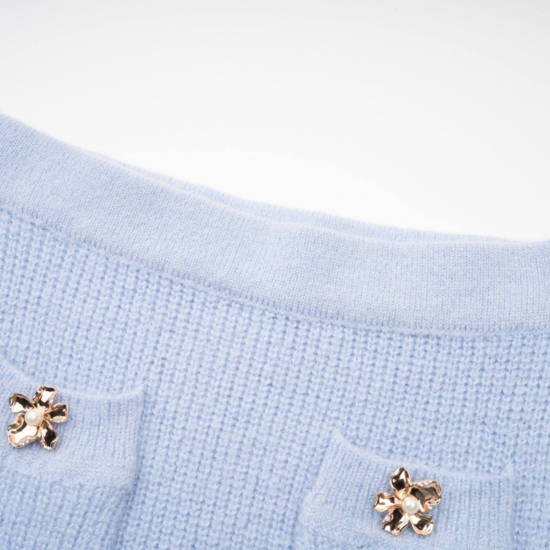 Woman wearing a blue knit blouse and matching skirt set standing against a plain background