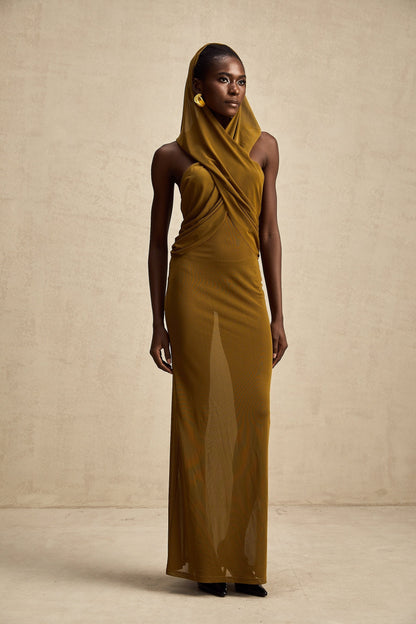 Woman wearing a long flowing maxi dress with a hooded design and crossover neckline revealing an open back