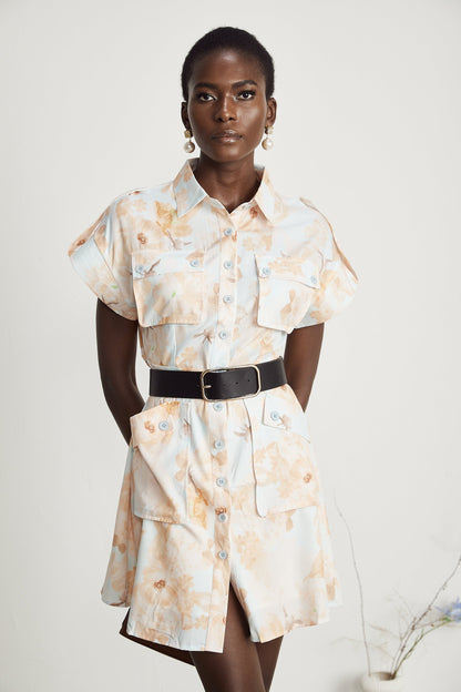 Woman wearing a short white shirt dress with a belt at the waist and buttonup front