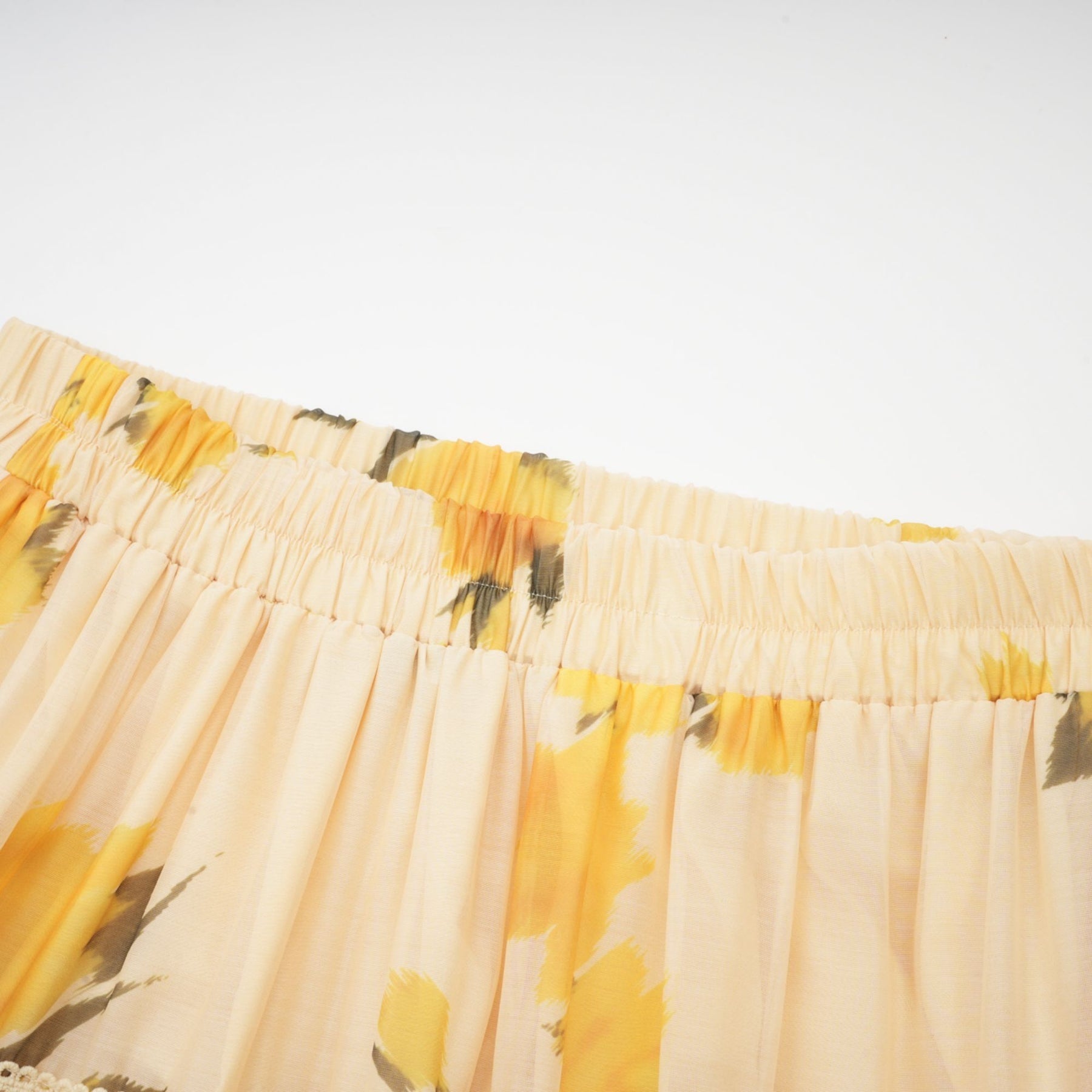 Yellow sunflower print pleated skirt closeup on white background