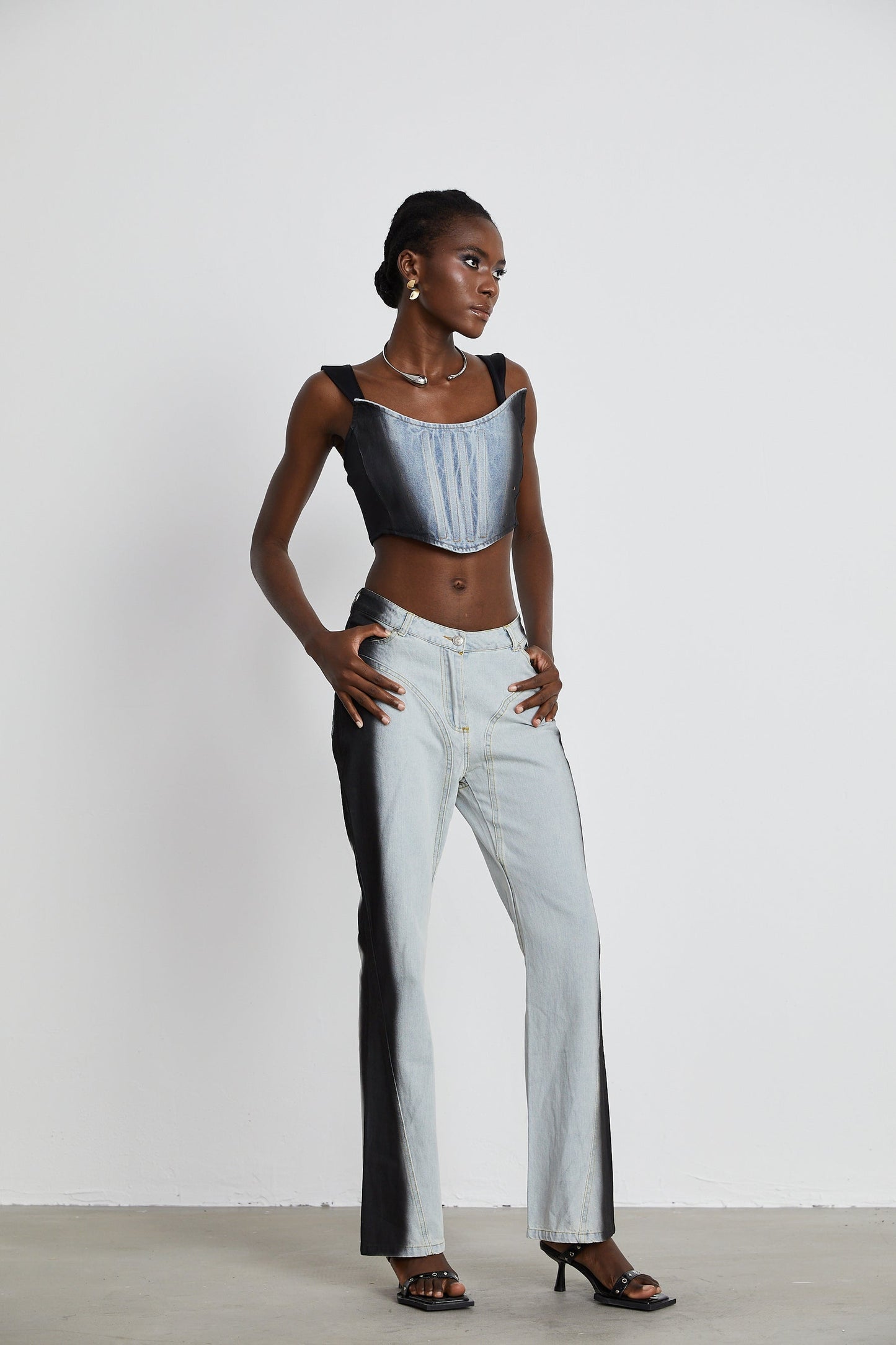 Woman wearing blue and white twotone wideleg jeans standing against neutral background